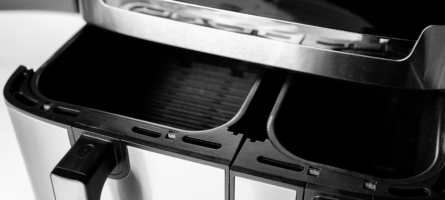Modern black air fryer with an open basket on a clean kitchen worktop, illustrating how to clean an air fryer.